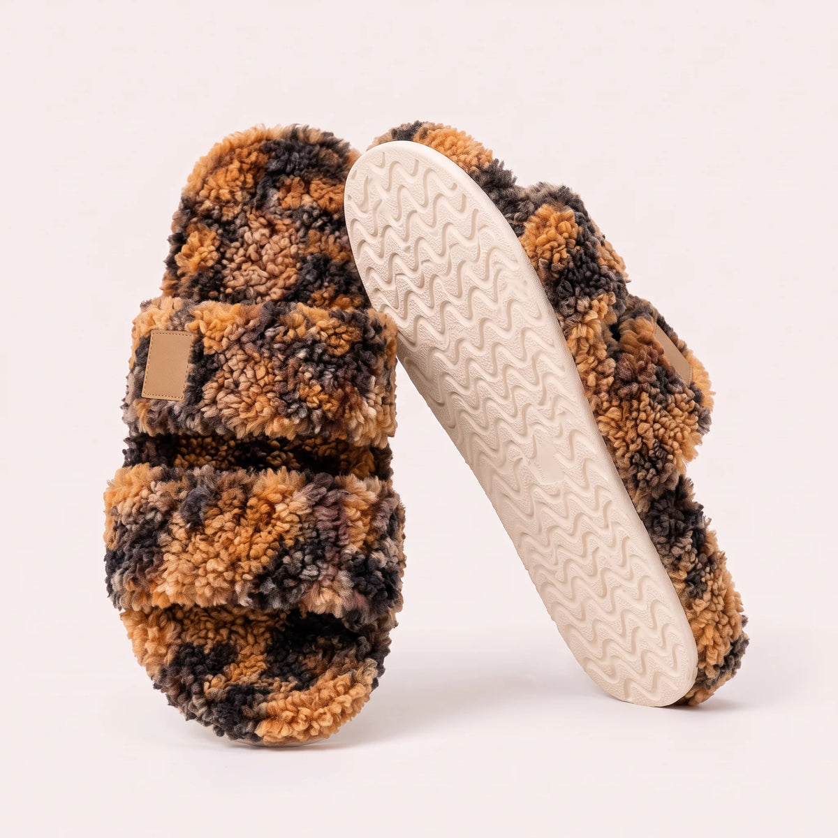 Fuzzy two-strap slides in Tortoise, one flat and one tilted to show the wavy cream sole