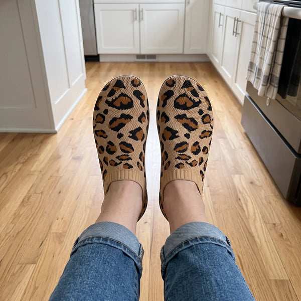Top view of leopard brown Cloud Sock Shoes with a wide rounded toe box on a wood floor