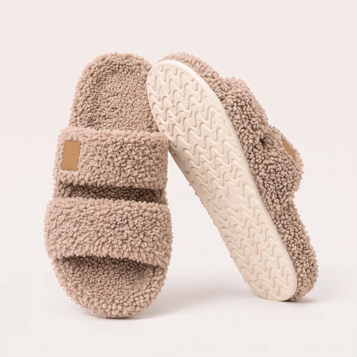 Fuzzy two-strap slides in Coffee, one flat and one tilted to show the wavy cream sole